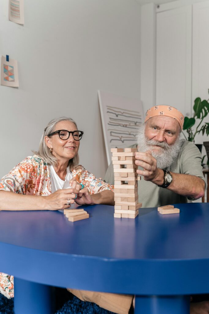 demencija - stariji muškarac i žena igraju igru slaganja drvenih figurica (Jenga)